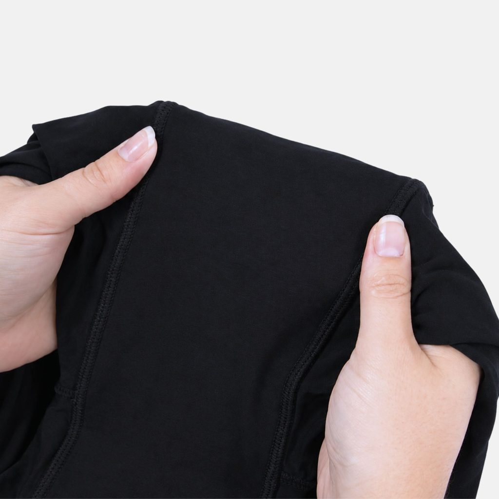 Hands holding open the gusset of the Her Bloom Shortie in black, showing the stitched absorbent panel