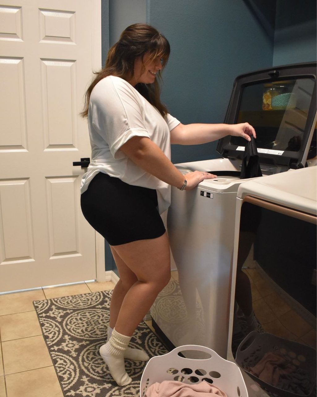 A woman loading a pair of black Her Bloom period underwear into a top-loading washing machine