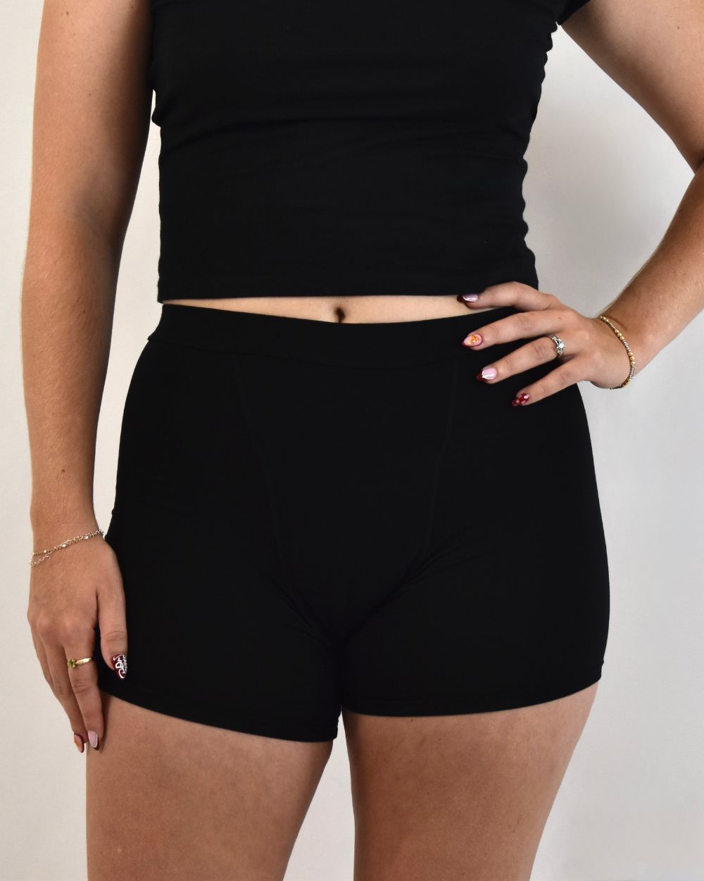 The Shortie in black, front view worn on model with a black top