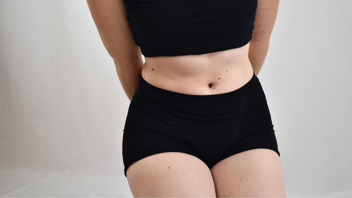 A woman seated in the black Her Bloom Shortie and a crop top